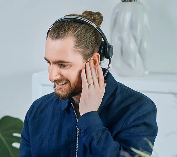 Man med hörlurar håller sig för örat